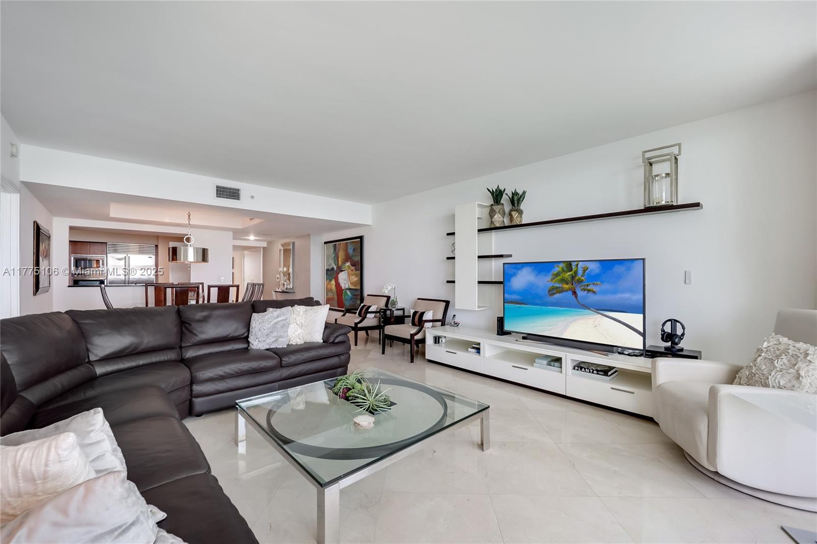 A living room features a dark leather sectional, glass coffee table, and a wall-mounted television — 1331 Brickell Bay Dr # 2605, Miami FL 33131, MIAMI, FL
