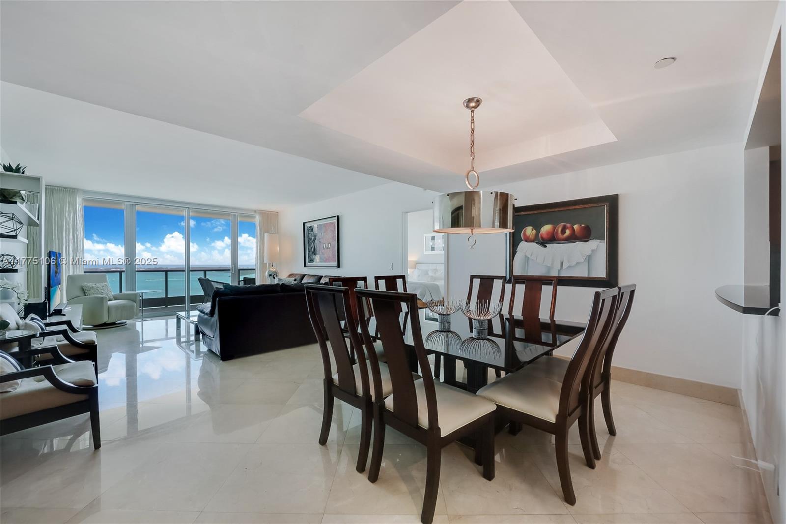 A dining area with a glass table and dark chairs sits before a living room — 1331 Brickell Bay Dr # 2605, Miami FL 33131, MIAMI, FL