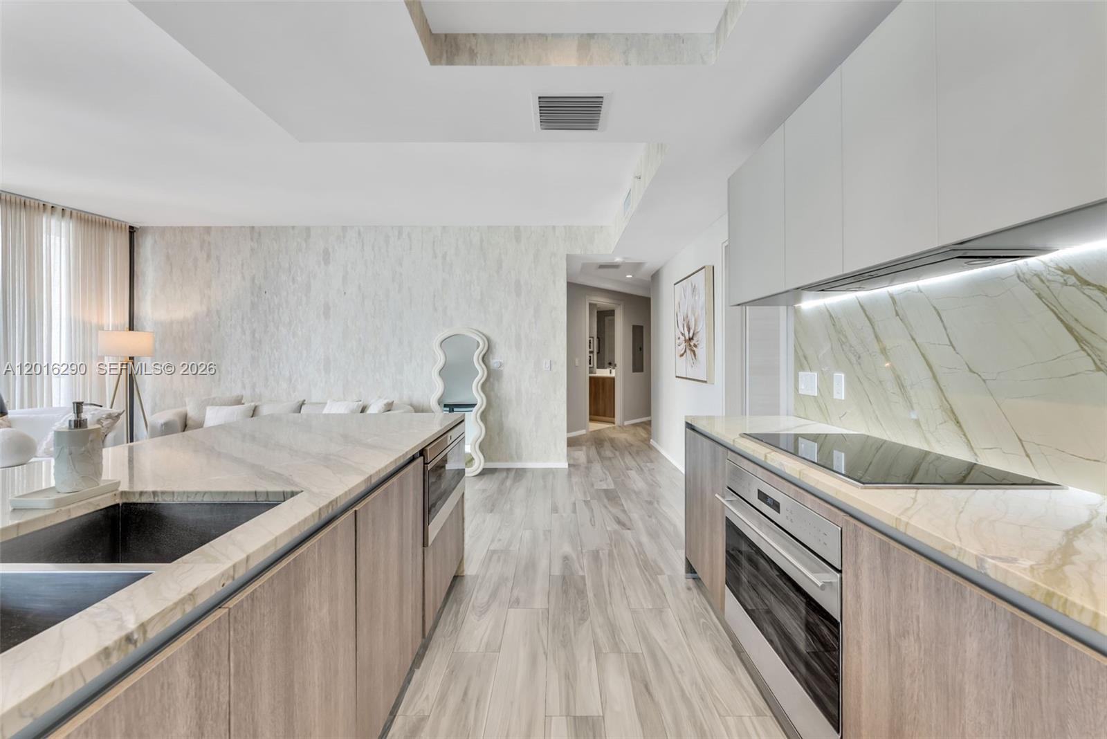 A modern kitchen features wood-toned cabinetry, marble countertops, and a matching marble backsplash — 801 S Miami Ave # 1805, Miami FL 33130, MIAMI, FL