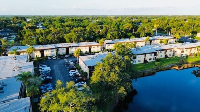 An aerial view shows multi-story apartment buildings situated next to a large pond — 625 N KEENE ROAD UNIT T5, CLEARWATER, FL