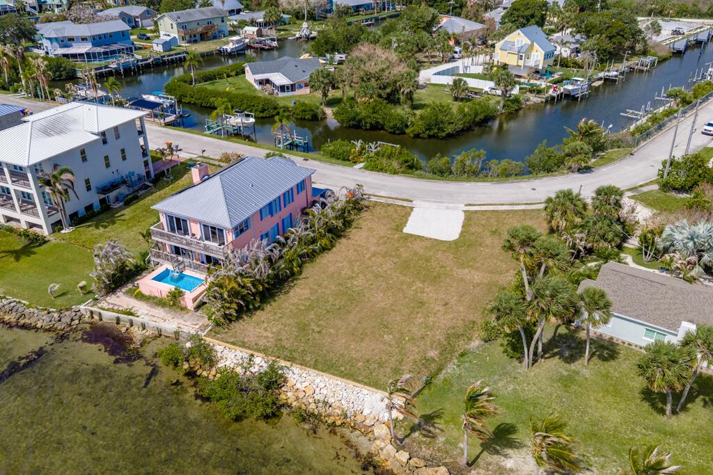 An aerial view shows a waterfront house with a pool next to a vacant lot — SEBASTIAN, FL