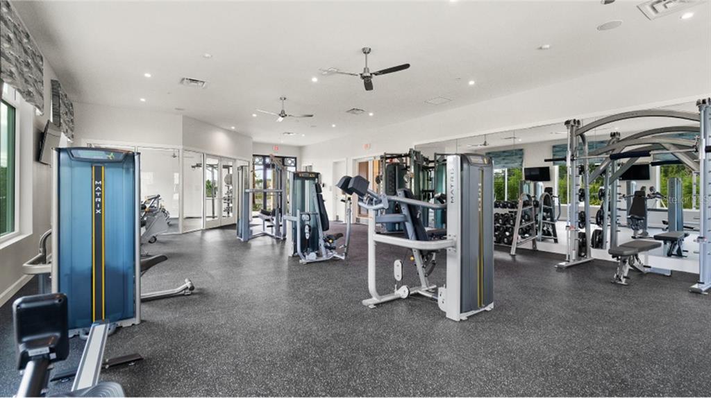 A bright fitness center features various Matrix exercise machines on a dark rubber floor — 6053 MEDITATION DRIVE, CLERMONT, FL