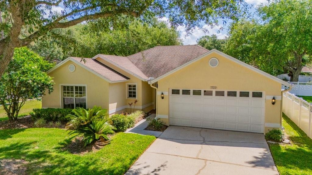 A yellow single-story house with a two-car garage and a concrete driveway — 17610 ESPRIT DRIVE, TAMPA, FL