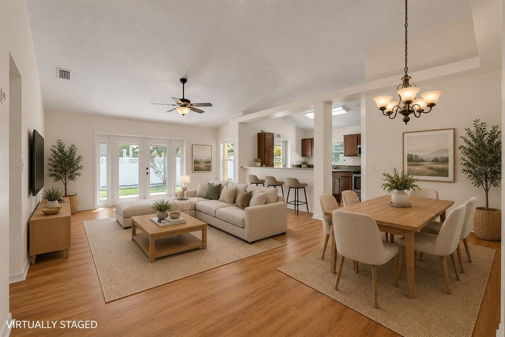 A virtually staged open-concept living and dining area with light wood floors and neutral furniture — 17610 ESPRIT DRIVE, TAMPA, FL