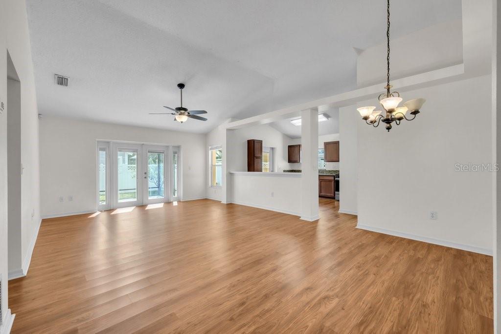 A spacious living room with light wood flooring, a ceiling fan, and a dining area — 17610 ESPRIT DRIVE, TAMPA, FL