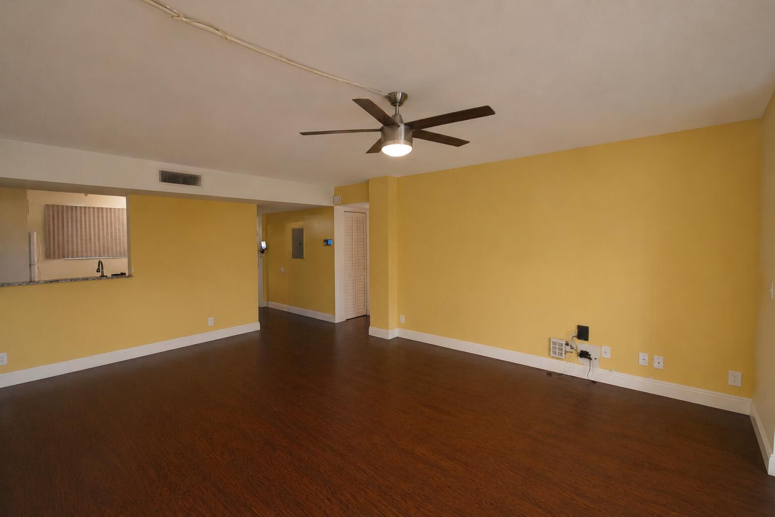 An empty room with yellow walls, dark wood flooring, and a ceiling fan — 5220 Las Verdes Circle # 220, Delray Beach FL 33484, DELRAY BEACH, FL