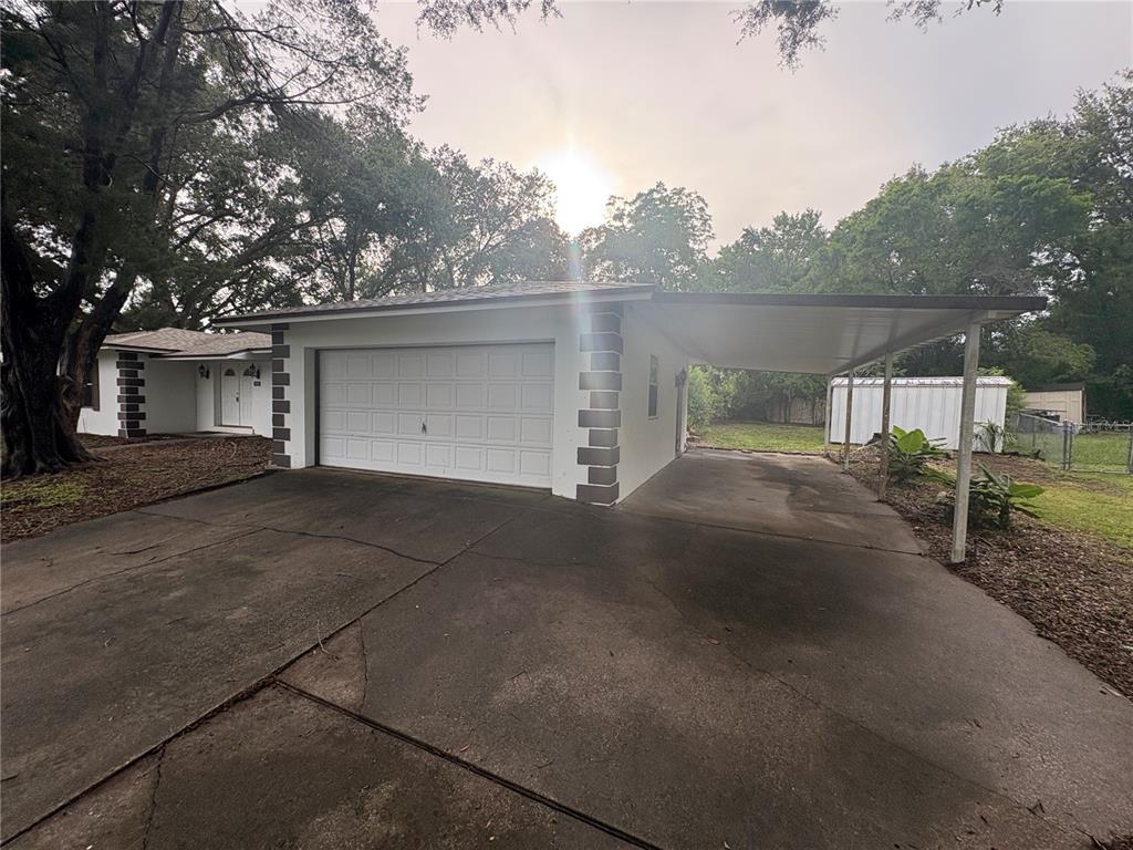 A white garage with a side carport sits on a concrete driveway near a house — 9202 N ABBOT DRIVE, CITRUS SPRINGS, FL