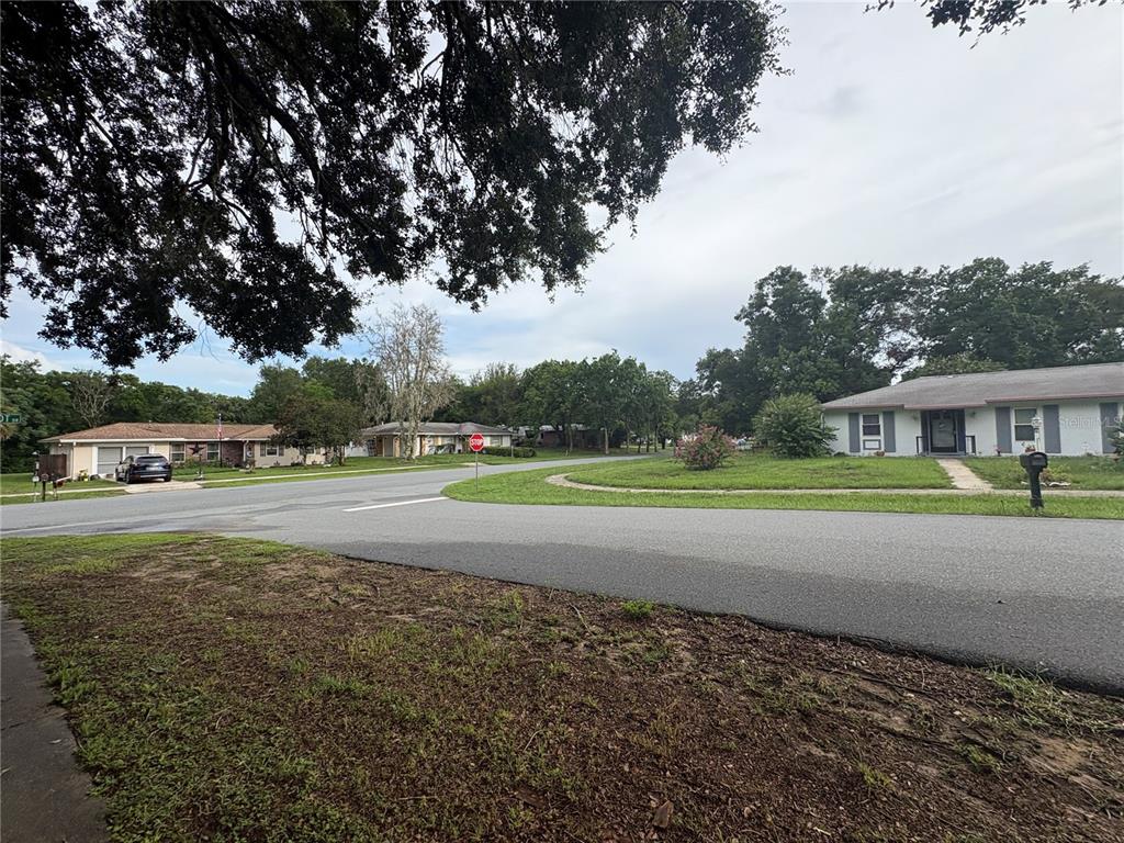 A view of a suburban street corner featuring houses, trees, and a stop sign — 9202 N ABBOT DRIVE, CITRUS SPRINGS, FL
