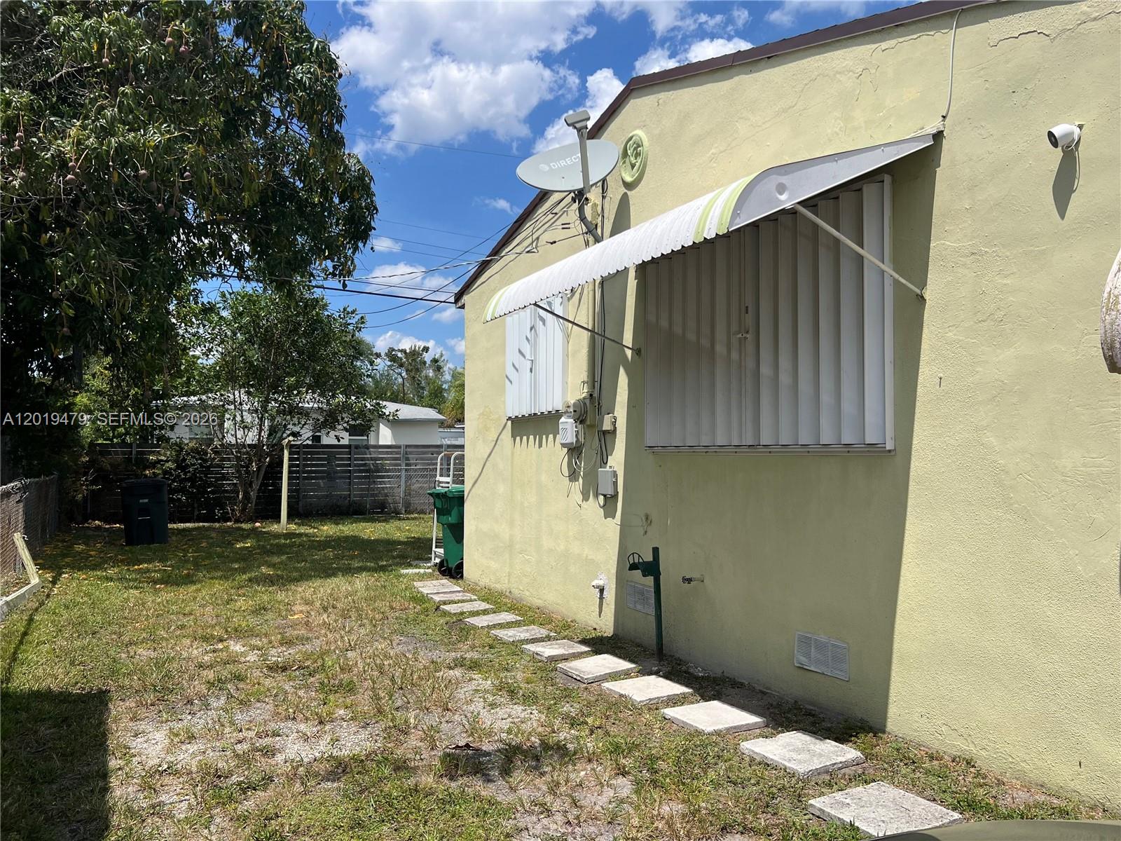 The exterior of a light green house features a window awning and a satellite dish — 1851 NW 51st Ter, Miami FL 33142, MIAMI, FL