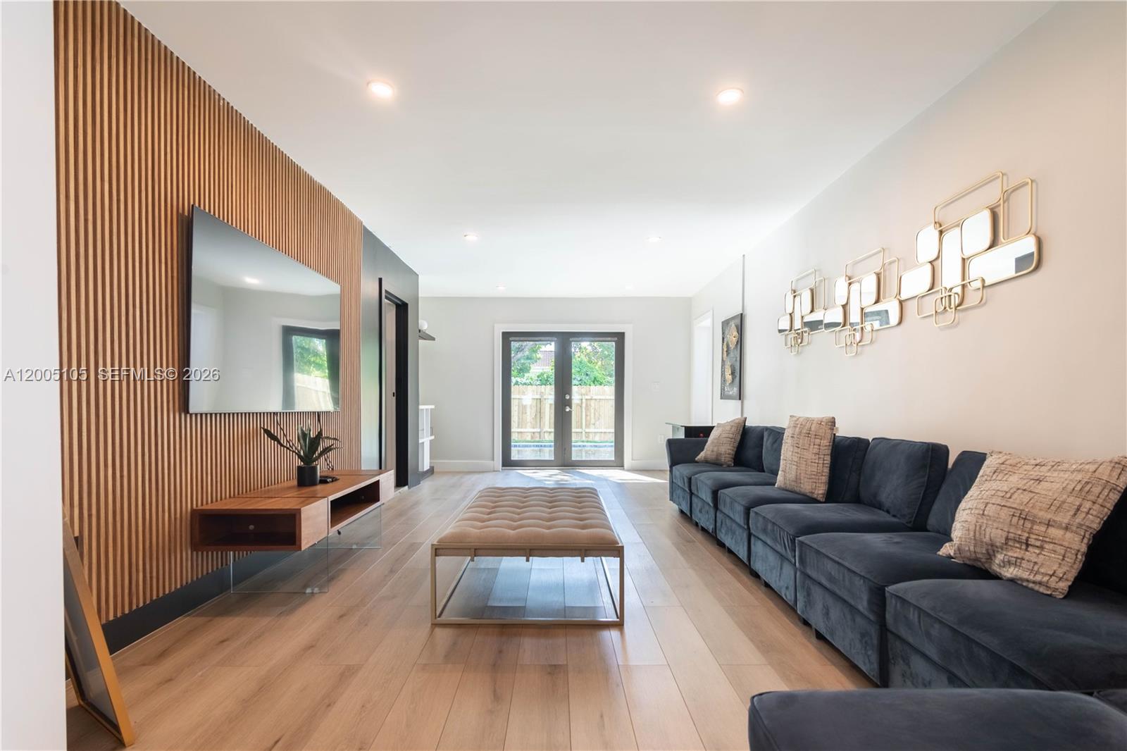 A living room features a slatted wood accent wall, a blue sofa, and glass doors — 2360 SW 12th St, Miami FL 33135, MIAMI, FL