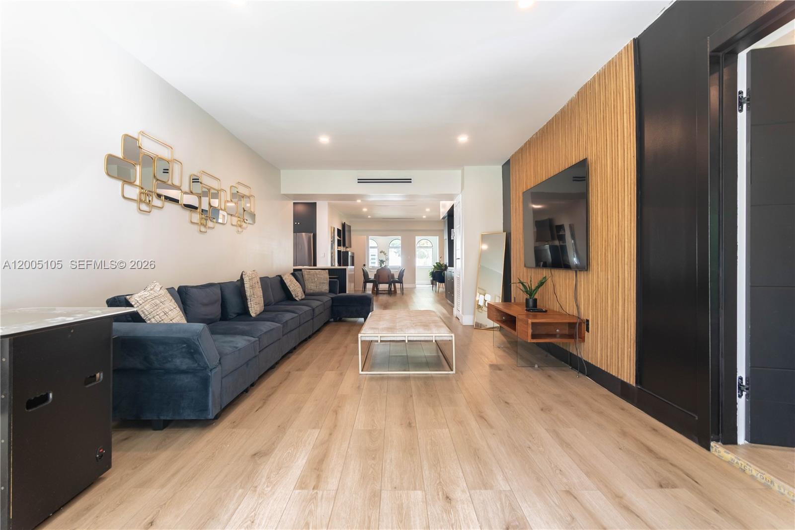 A living room features a blue sectional sofa, wood-slat accent wall, and light wood flooring — 2360 SW 12th St, Miami FL 33135, MIAMI, FL