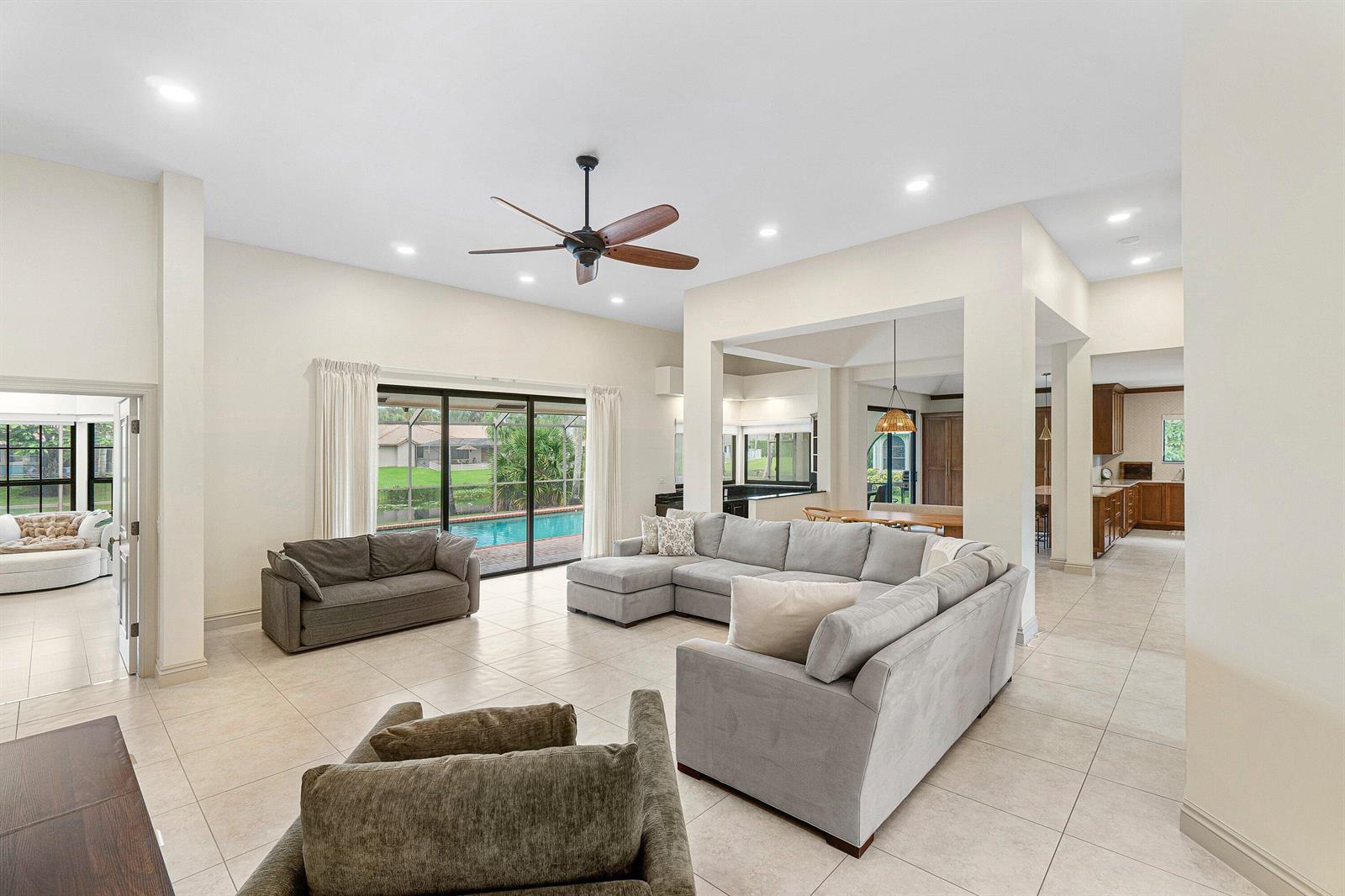 A spacious living room features a large gray sectional sofa, tile flooring, and a ceiling fan — 3615 SW 24th Lane, Delray Beach FL 33445, DELRAY BEACH, FL
