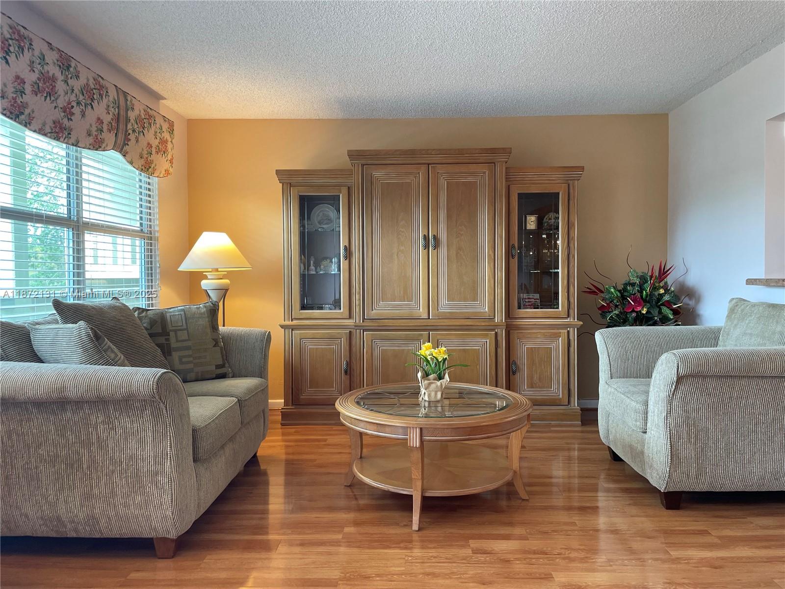 A living room features a wooden entertainment center, two upholstered sofas, and a round coffee table — 3033 Berkshire B # 3033, Deerfield Beach FL 33442, DEERFIELD BEACH, FL