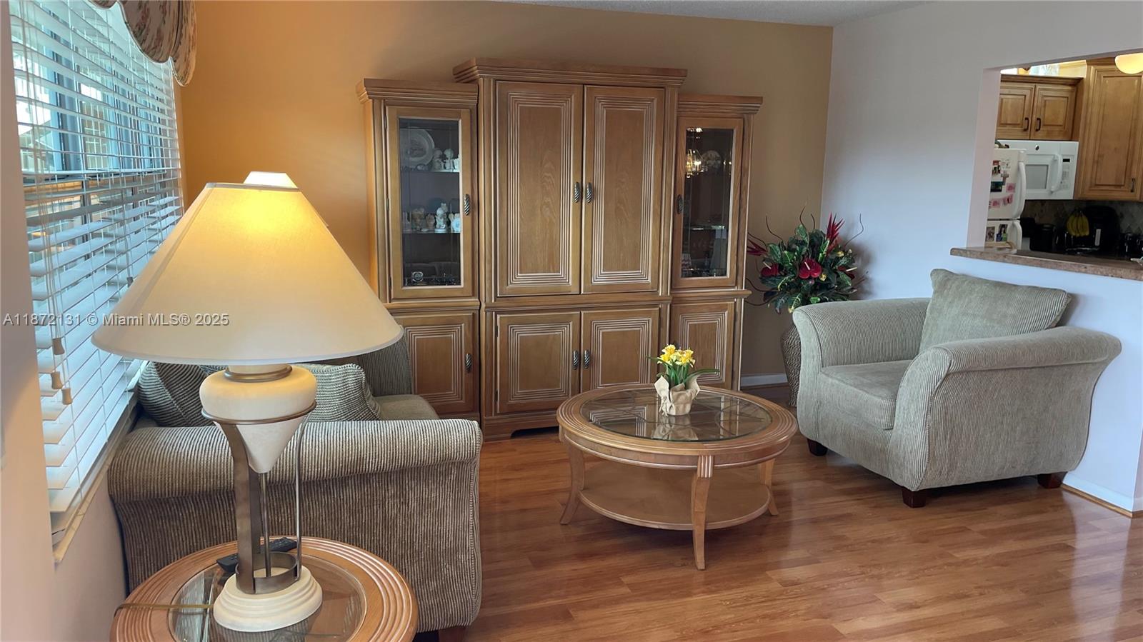 A living room features wood flooring, a large hutch, two armchairs, and a glass-topped table — 3033 Berkshire B # 3033, Deerfield Beach FL 33442, DEERFIELD BEACH, FL