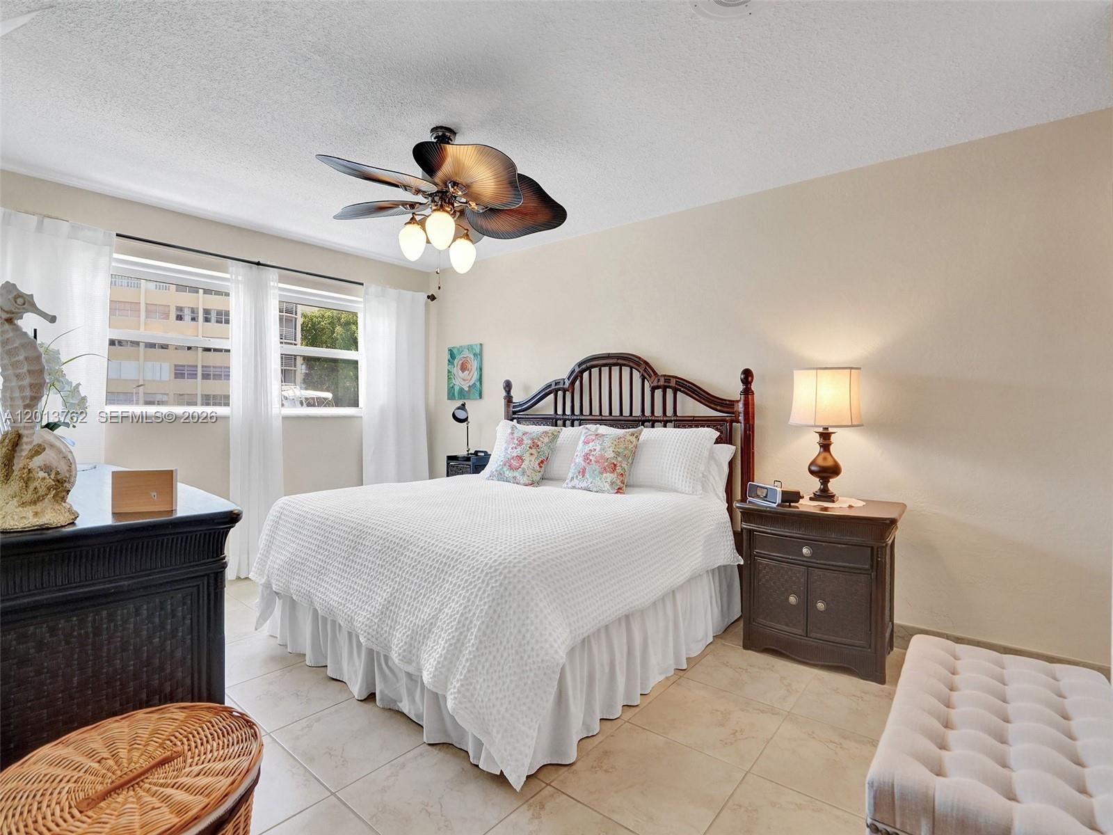 A bedroom features a wooden bed frame, a ceiling fan, and tile flooring — 2600 Diana Dr # 105, Hallandale Beach FL 33009, HALLANDALE BEACH, FL