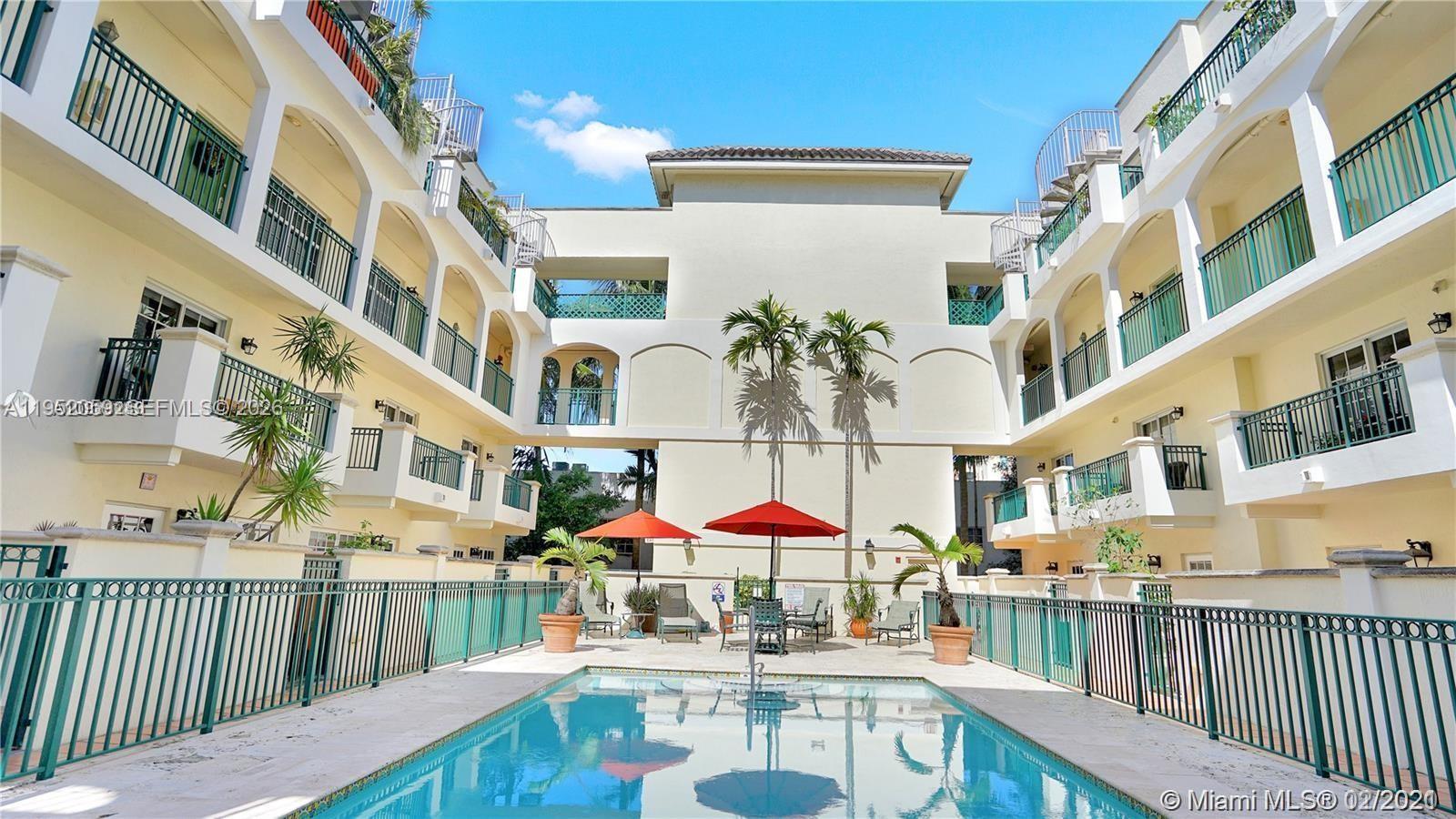 A swimming pool sits in the courtyard of a multi-story apartment building with balconies — 300 Euclid Ave # 209, Miami Beach FL 33139, MIAMI BEACH, FL