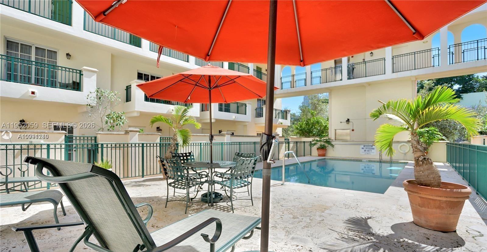 A swimming pool area features patio furniture, orange umbrellas, and potted palm trees — 300 Euclid Ave # 209, Miami Beach FL 33139, MIAMI BEACH, FL