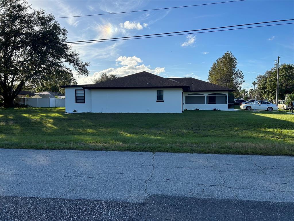 A single-story house with a white exterior, a dark roof, and a screened-in porch — 602 MESILLA DRIVE, KISSIMMEE, FL