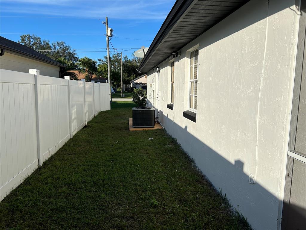 A side yard features a white vinyl fence, a stucco house wall, and an air conditioner — 602 MESILLA DRIVE, KISSIMMEE, FL