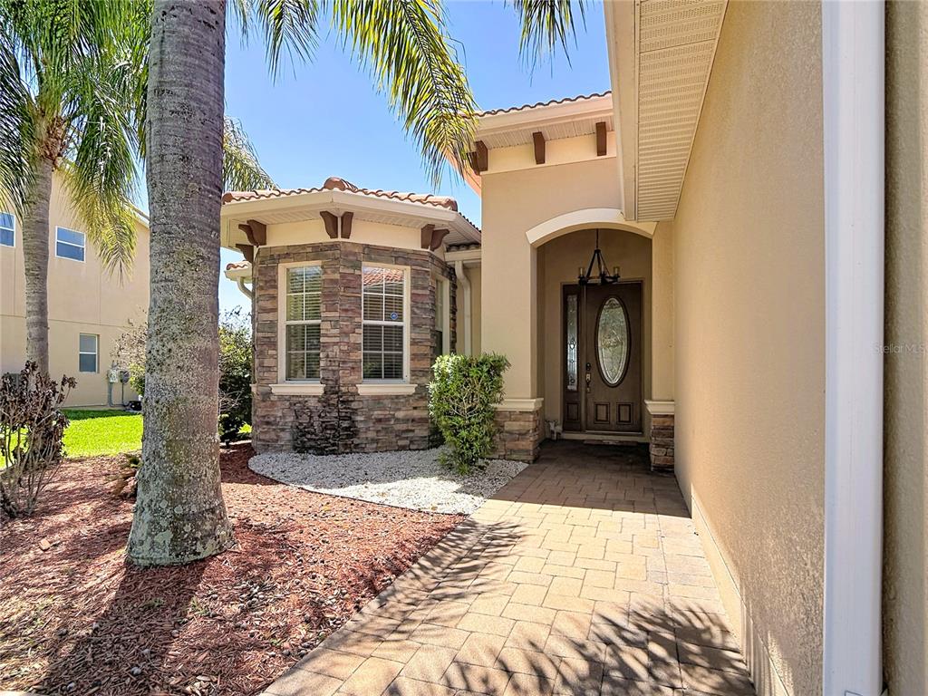 A stone-accented house exterior features a paved walkway leading to a brown front door — 3843 GOLDEN KNOT DRIVE, KISSIMMEE, FL