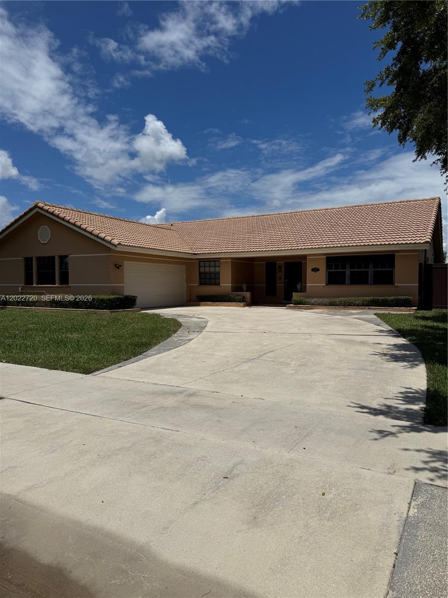 A single-story house with a tan exterior, tile roof, and a concrete driveway — 6950 W Wedgewood Ave, Davie FL 33331, DAVIE, FL