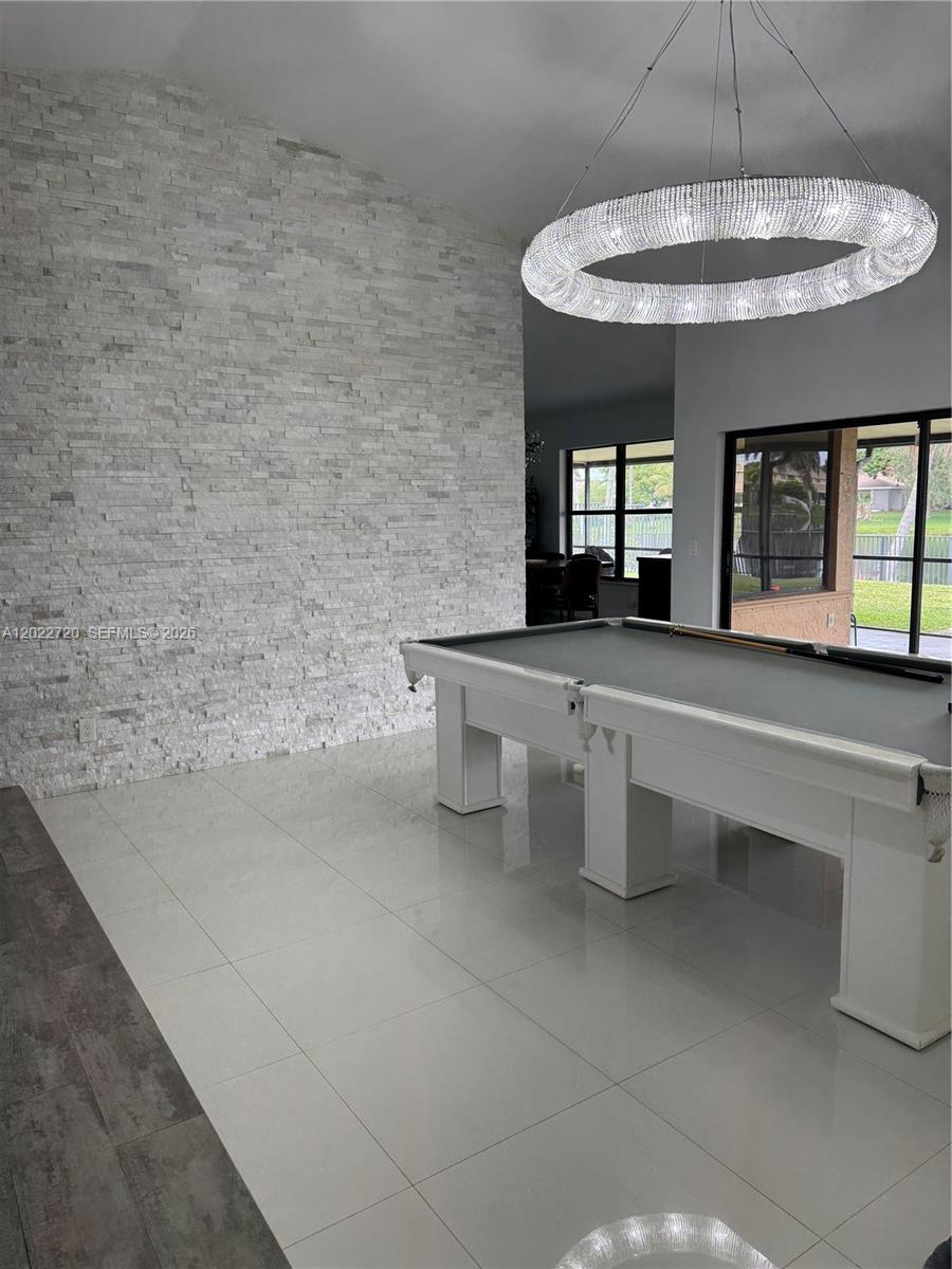 A room features a pool table, a large crystal chandelier, and a white stone wall — 6950 W Wedgewood Ave, Davie FL 33331, DAVIE, FL