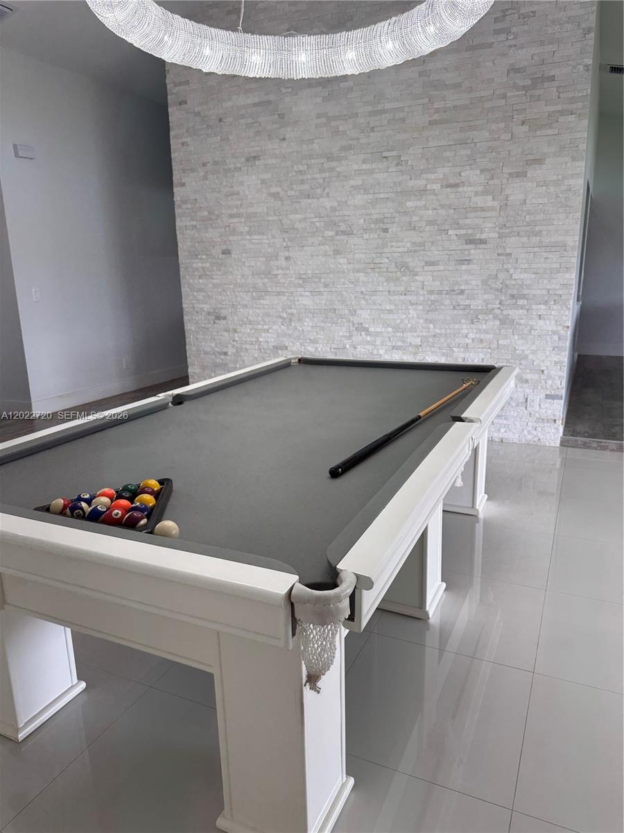 A white pool table with a grey felt surface sits in a room with stone walls — 6950 W Wedgewood Ave, Davie FL 33331, DAVIE, FL