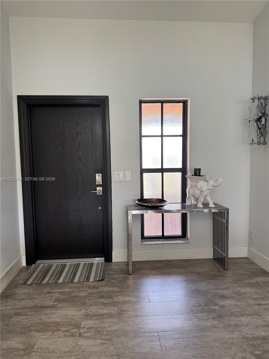 An entryway features a black door, a tall window, a metal console table, and wood-look flooring — 6950 W Wedgewood Ave, Davie FL 33331, DAVIE, FL