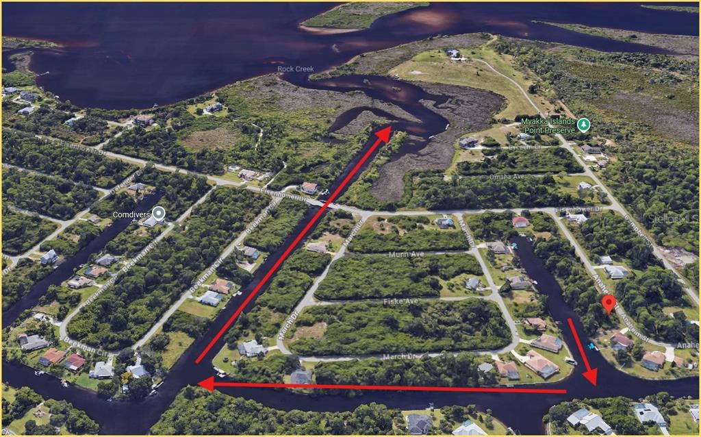 An aerial view shows a residential neighborhood with canals, vegetation, and a nearby nature preserve — 1144 ANAHEIM STREET, PORT CHARLOTTE, FL