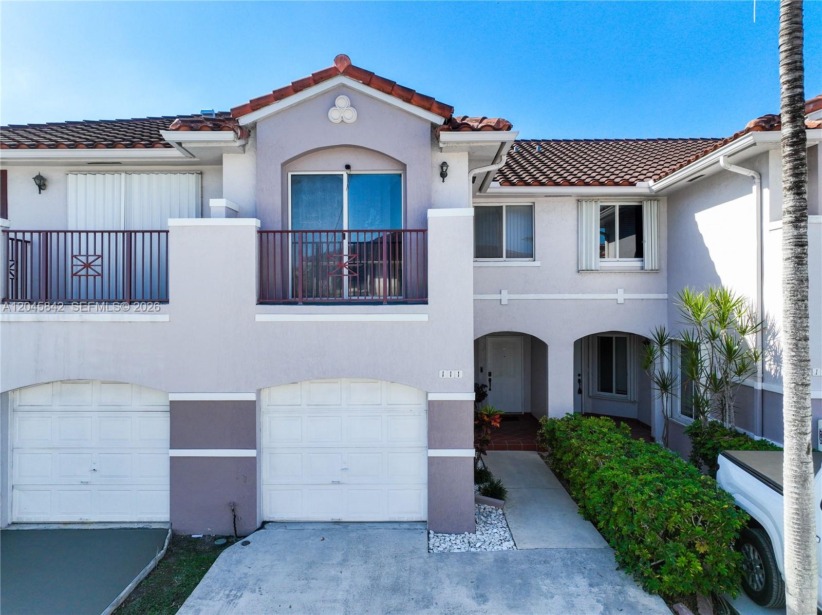 A two-story townhouse exterior features a garage, a second-floor balcony, and a tiled roof — 10210 SW 154th Pl # 111, Miami FL 33196, MIAMI, FL