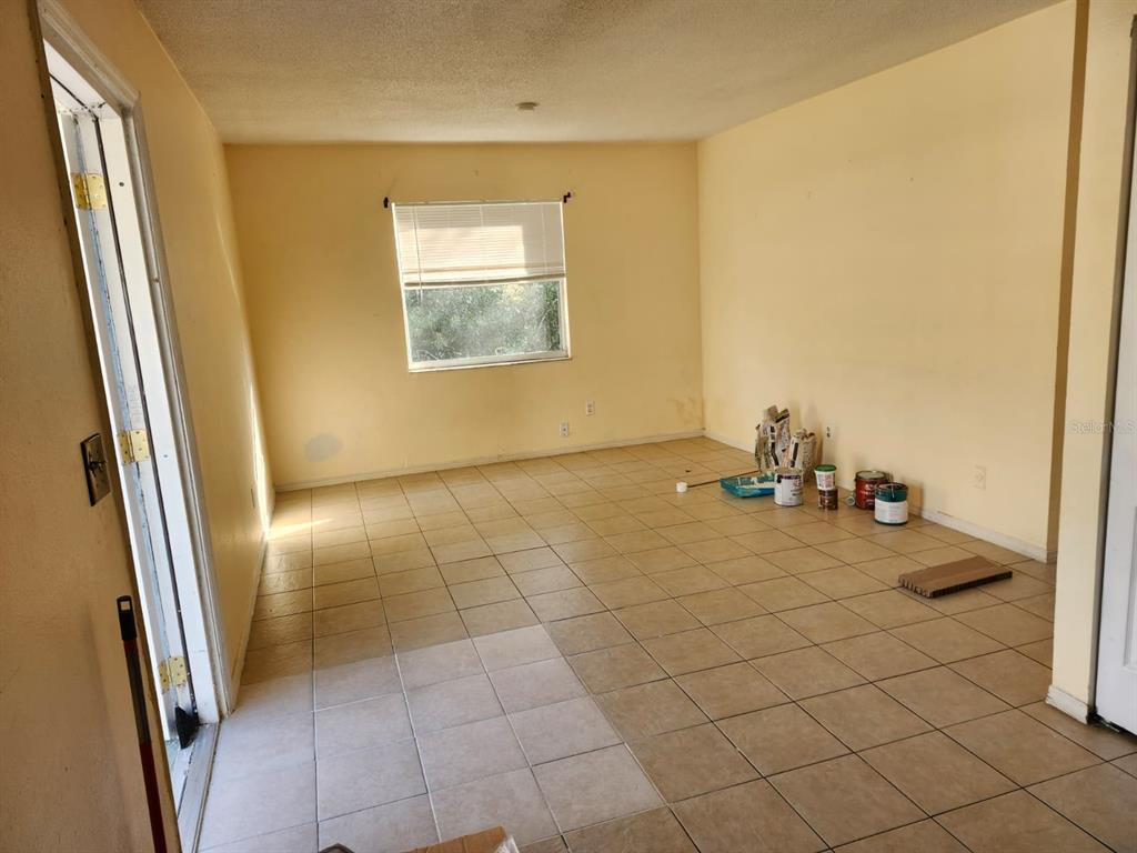 An empty room with beige walls, tiled flooring, and a window with blinds — 736 MICHIGAN COURT UNIT 4, ST CLOUD, FL