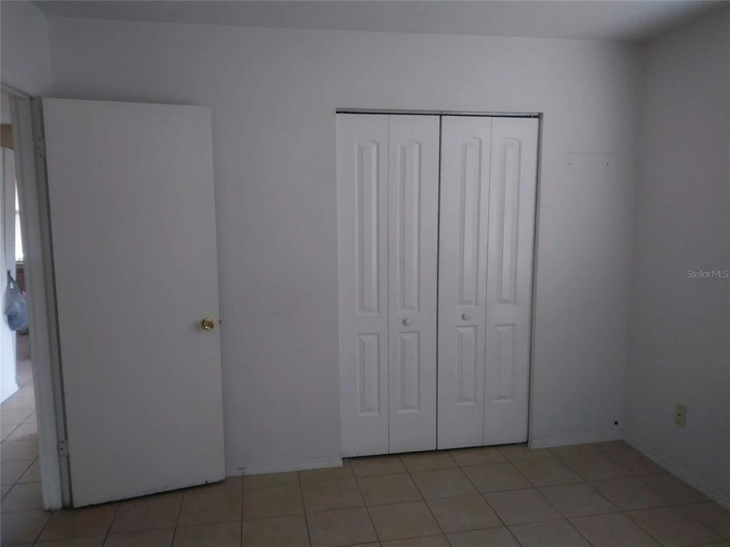 A room with light-colored walls, tiled flooring, a standard door, and a white bifold closet — 736 MICHIGAN COURT UNIT 4, ST CLOUD, FL