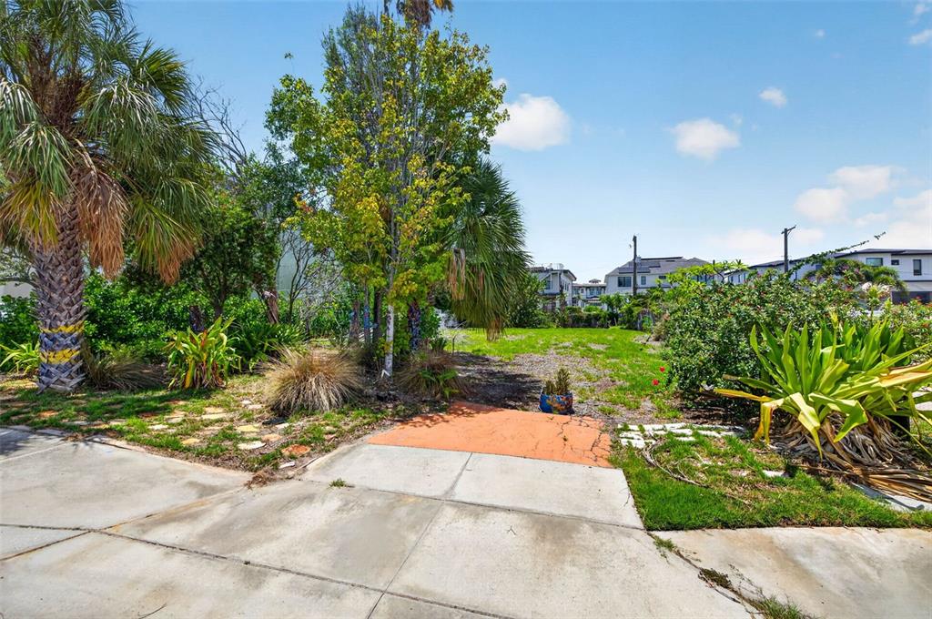 An empty residential lot features a concrete driveway, landscaping, and mature trees — 830 S DAVIS BOULEVARD, TAMPA, FL