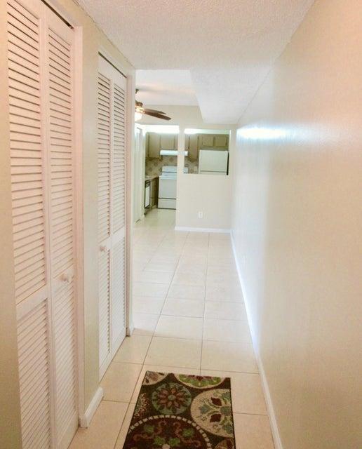 A hallway with louvered closet doors leads to a kitchen with white appliances and cabinets — CORAL SPRINGS, FL