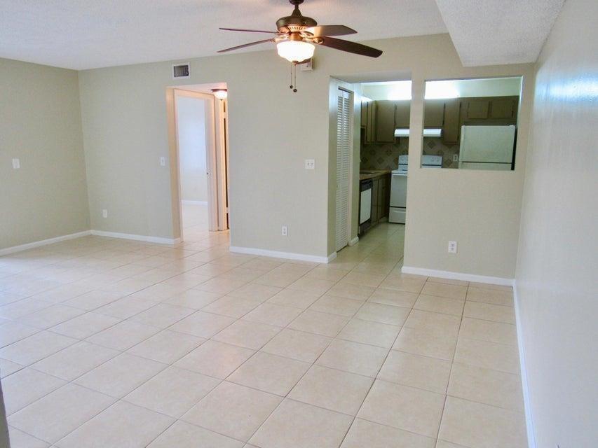 A living room with light-colored tile flooring, a ceiling fan, and an open kitchen pass-through — CORAL SPRINGS, FL