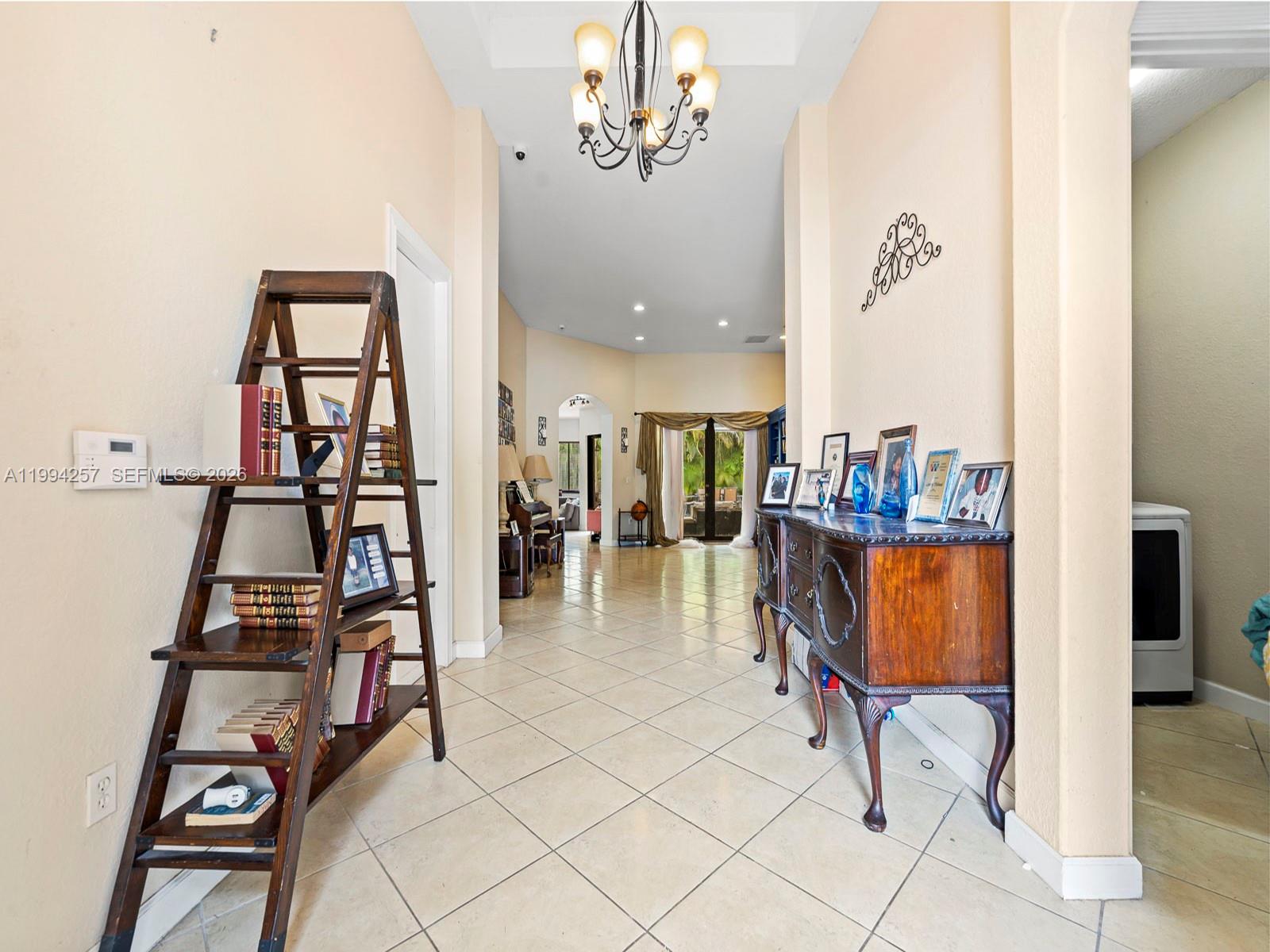 A tiled entryway features a wooden ladder shelf, a sideboard, and a chandelier — 19385 SW 79th Ct, Cutler Bay FL 33157, CUTLER BAY, FL