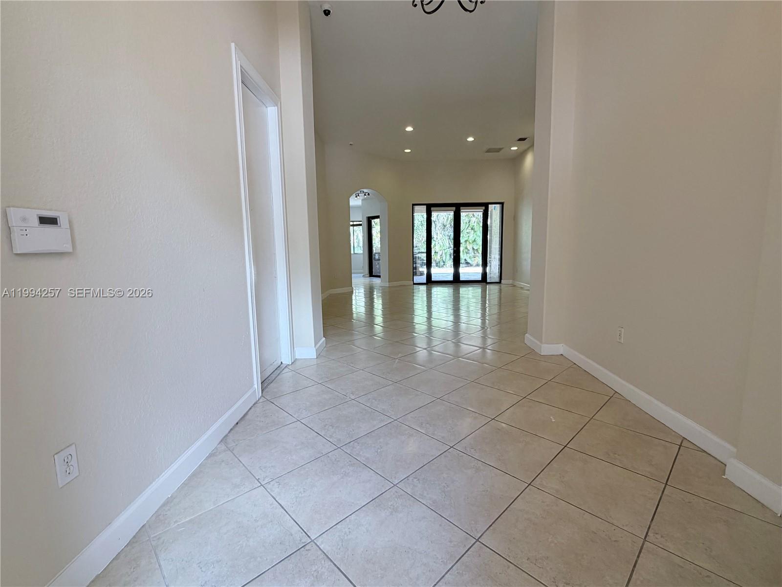 A tiled entryway leads to a living area with glass doors and arched doorways — 19385 SW 79th Ct, Cutler Bay FL 33157, CUTLER BAY, FL