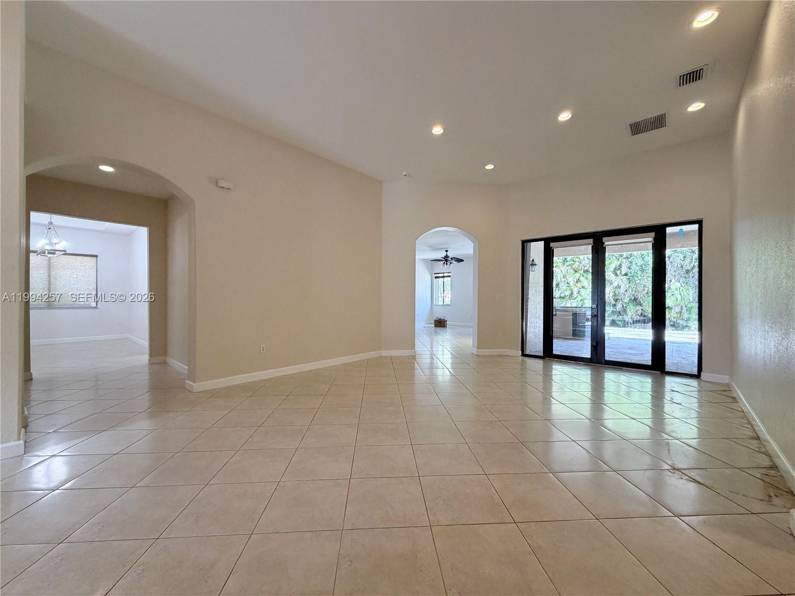 A spacious living area features beige tile flooring, recessed lighting, and glass sliding doors to outdoors — 19385 SW 79th Ct, Cutler Bay FL 33157, CUTLER BAY, FL