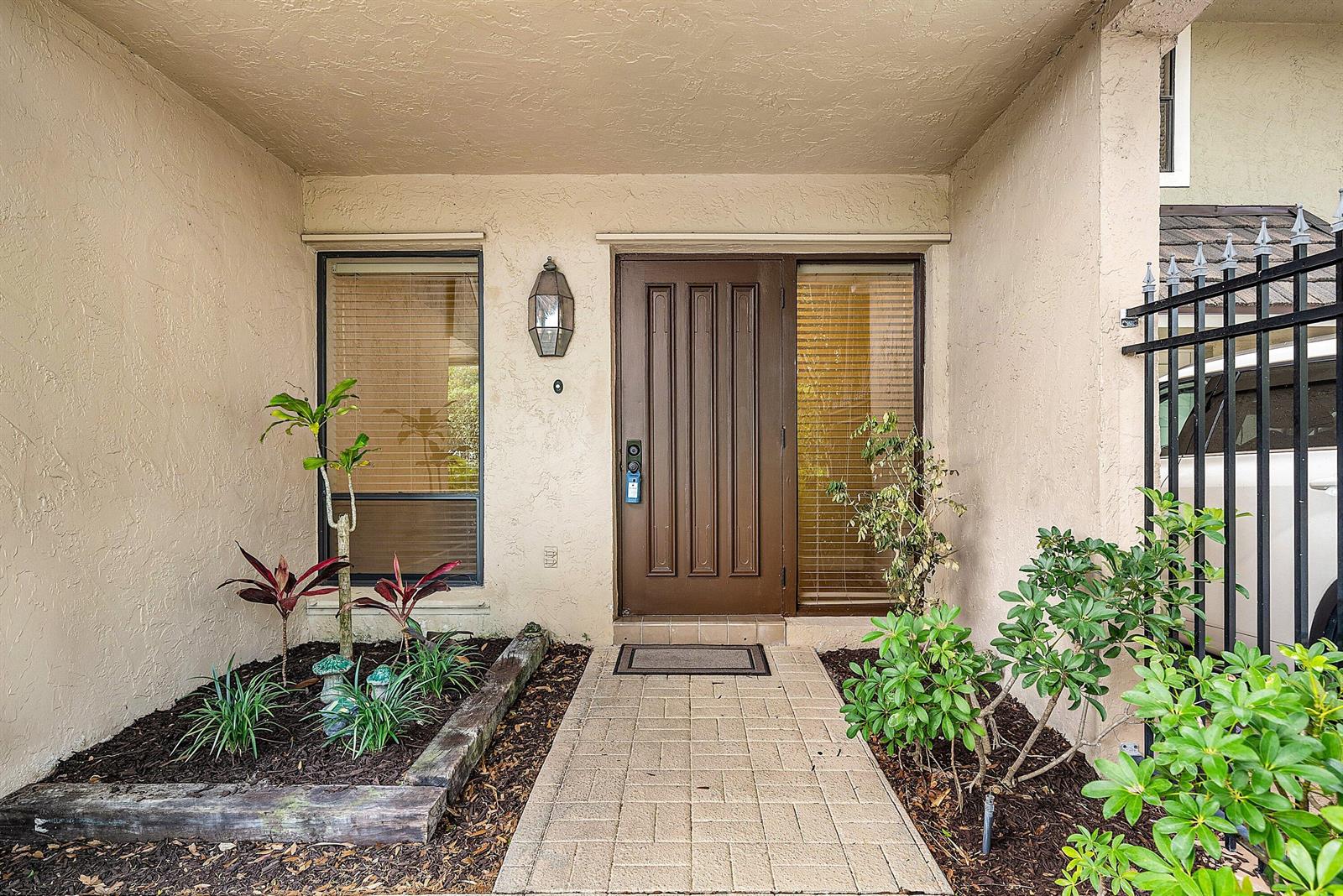 A front entryway features a brown door, a brick walkway, and landscaped garden beds — 5664 Santiago Circle, Boca Raton FL 33433, BOCA RATON, FL