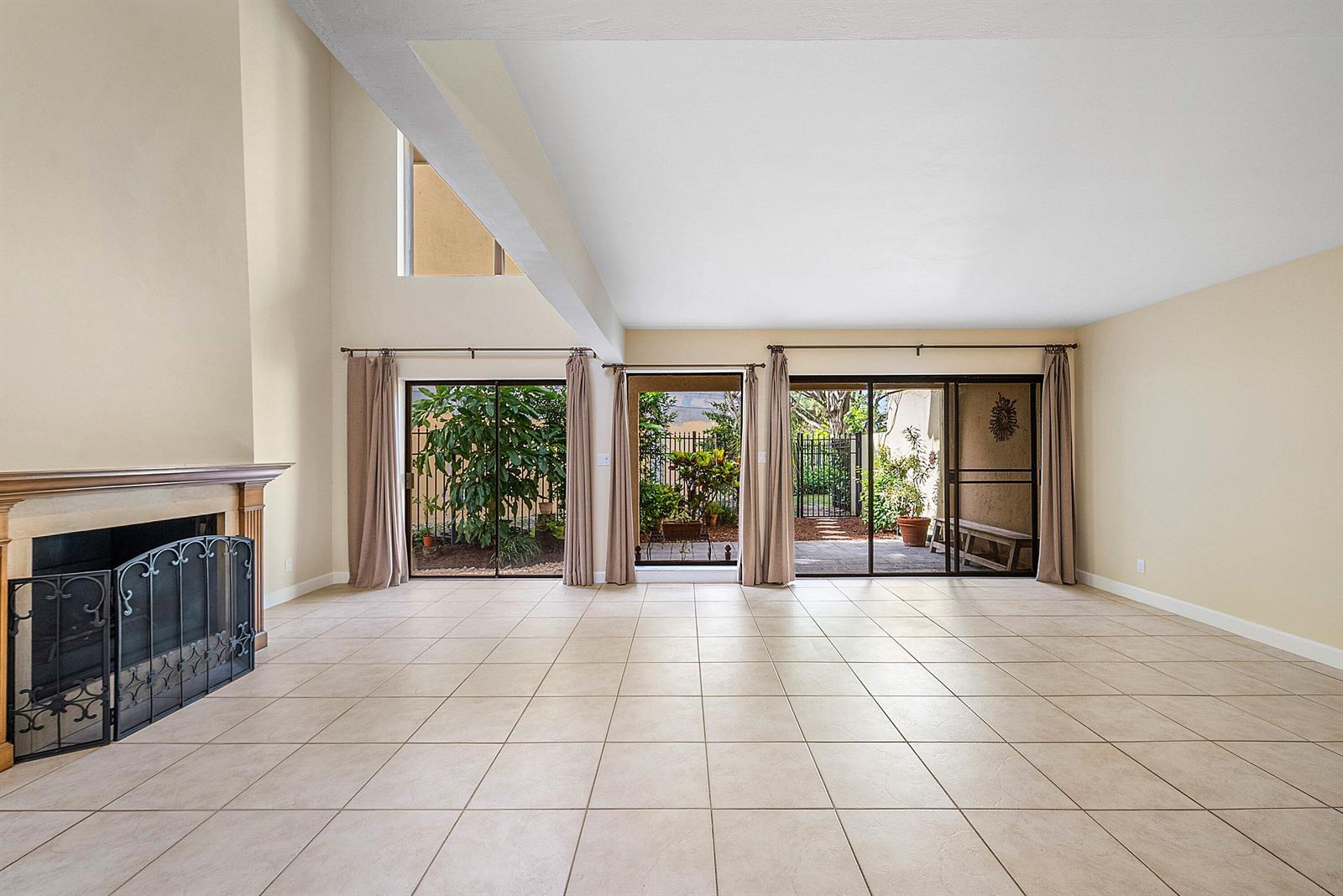 A spacious living room features beige tile floors, a fireplace, and sliding glass doors — 5664 Santiago Circle, Boca Raton FL 33433, BOCA RATON, FL