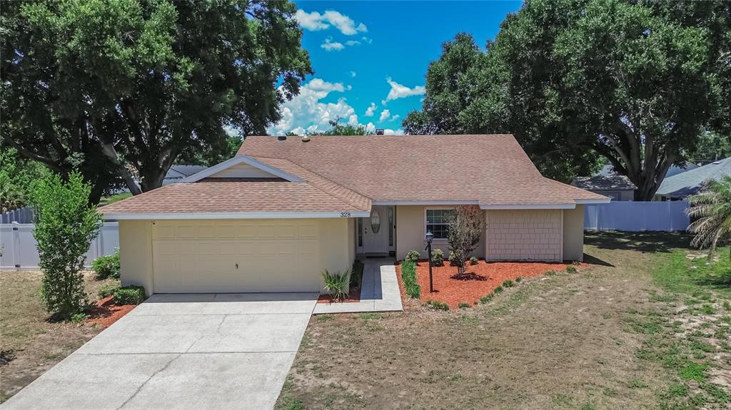 A single-story house with a tan exterior, brown shingled roof, and an attached two-car garage — 328 VAIL DRIVE, WINTER HAVEN, FL
