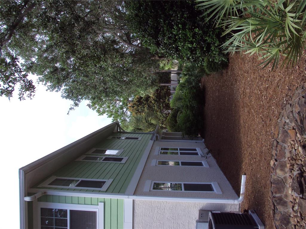 The side exterior of a two-story house with light green siding and a stucco base — 101 SAND OAK BOULEVARD, PANAMA CITY BEACH, FL