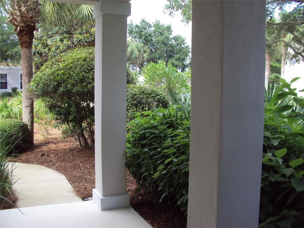 A view from a covered porch looking out toward a walkway and lush landscaping — 101 SAND OAK BOULEVARD, PANAMA CITY BEACH, FL