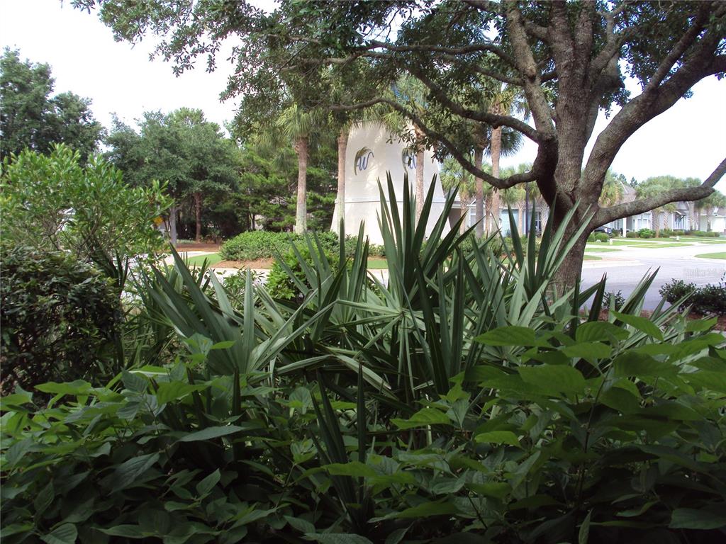 A neighborhood entrance sign stands behind lush green landscaping and a large tree — 101 SAND OAK BOULEVARD, PANAMA CITY BEACH, FL