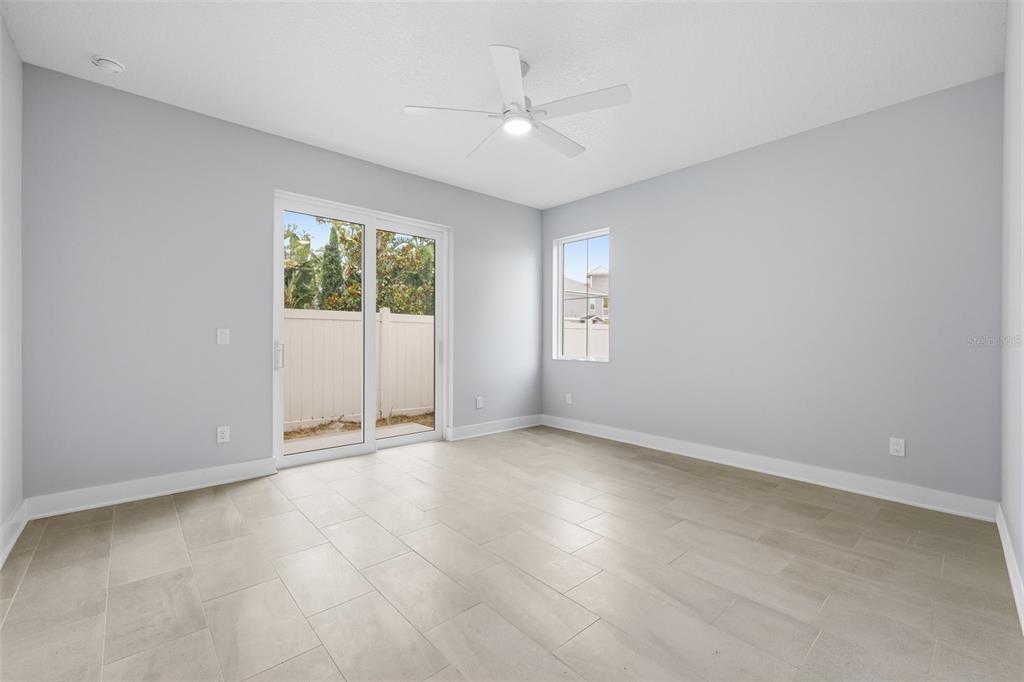 A bright room with light gray walls, tile flooring, a ceiling fan, and sliding glass doors — 4208 W CARMEN STREET UNIT D, TAMPA, FL