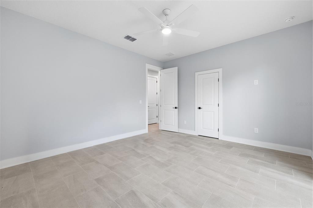 An empty bedroom features light gray walls, tile flooring, a ceiling fan, and two doors — 4208 W CARMEN STREET UNIT D, TAMPA, FL