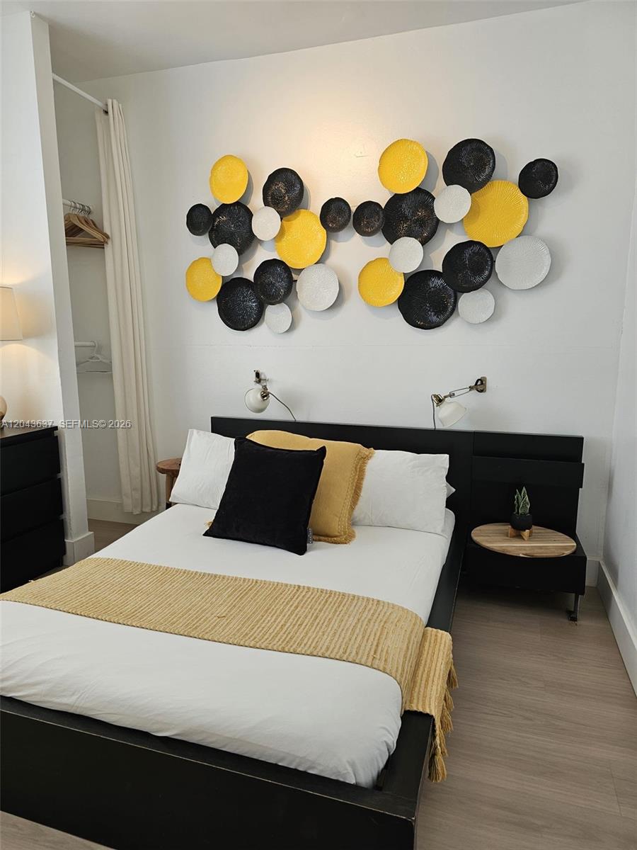 A bedroom features a bed with yellow and black accents and circular wall art — 750 Collins Ave # 306, Miami Beach FL 33139, MIAMI BEACH, FL
