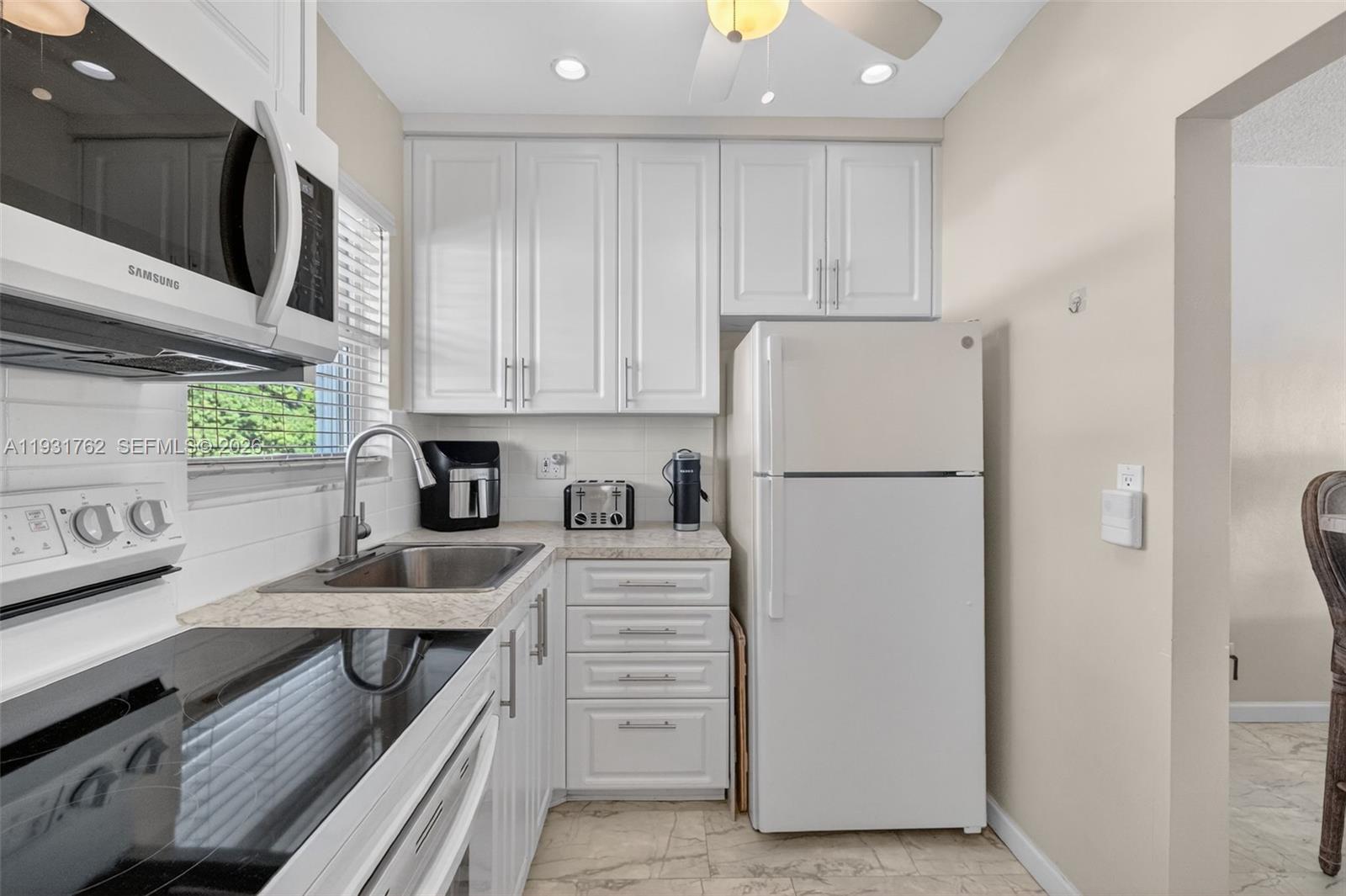 A small kitchen features white cabinets, stainless steel appliances, and a light-colored countertop — 2650 W Golf Blvd # 259, Pompano Beach FL 33064, POMPANO BEACH, FL