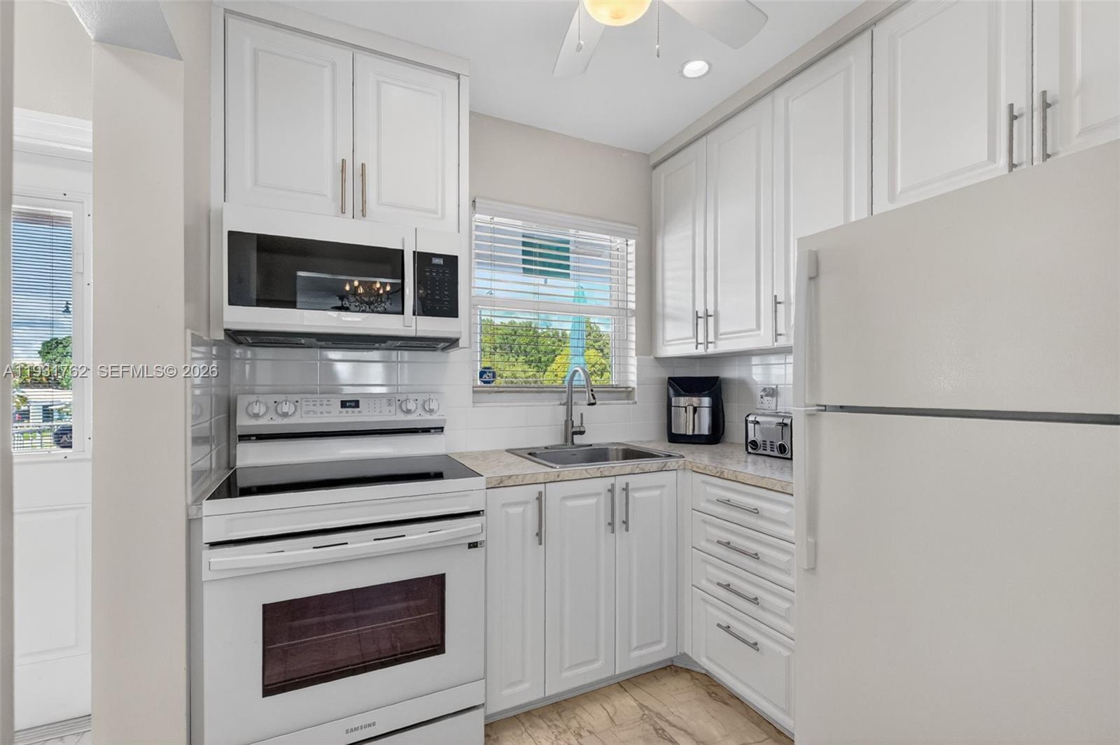 A white kitchen features white cabinets, stainless steel appliances, and a window above the sink — 2650 W Golf Blvd # 259, Pompano Beach FL 33064, POMPANO BEACH, FL