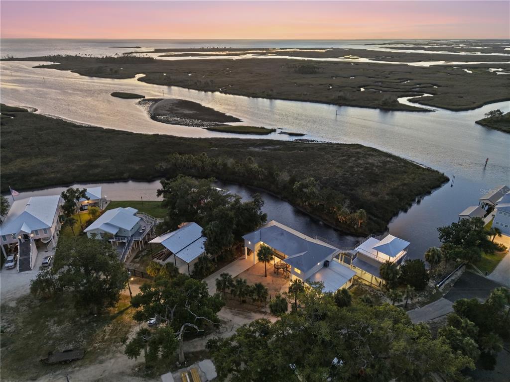 An aerial view shows several houses situated along a winding waterway near a coastal marsh — 38 SE 195TH STREET, SUWANNEE, FL